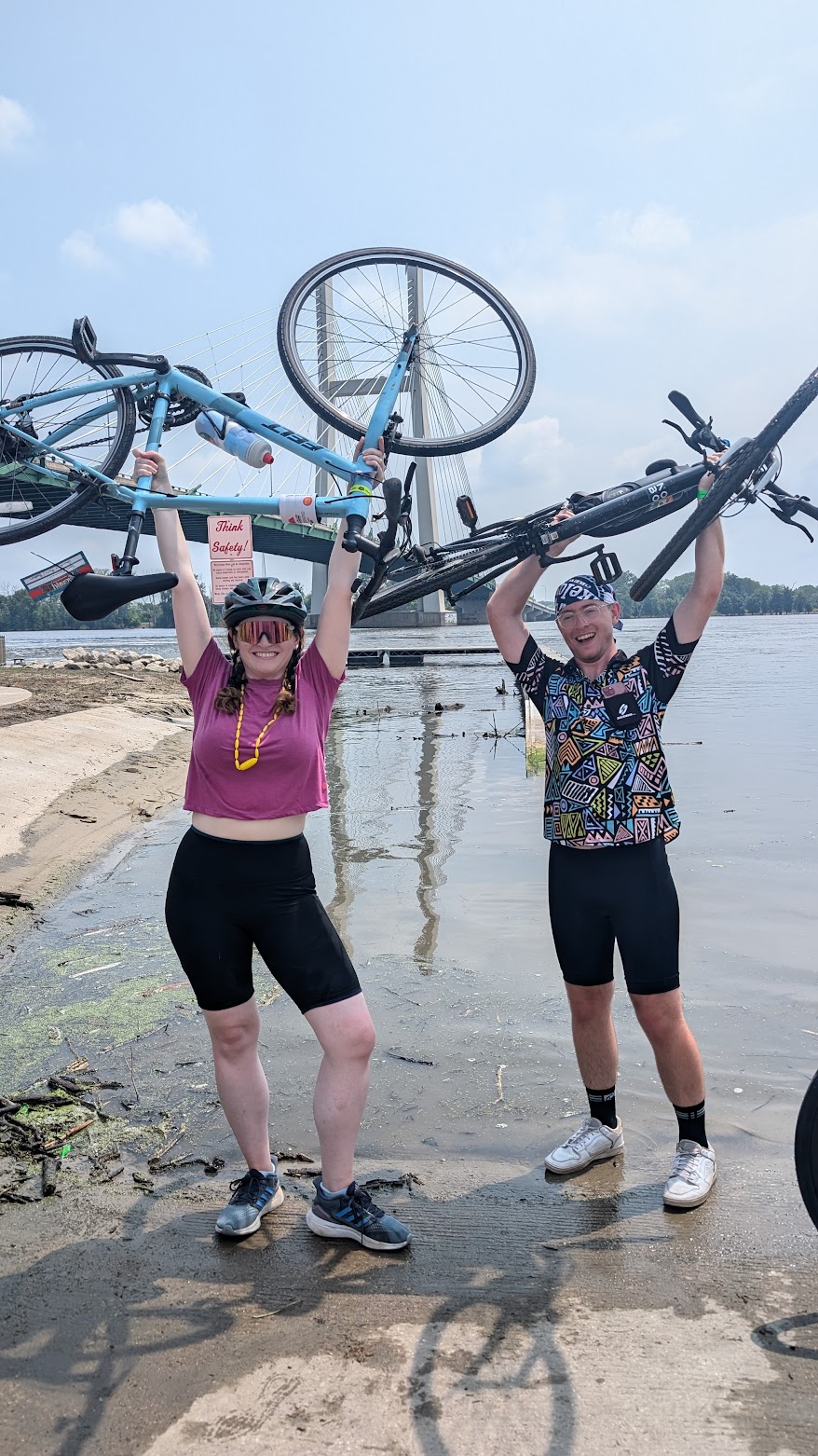 Image of Jenny and her brother, holding bikes above their head after biking across Iowa