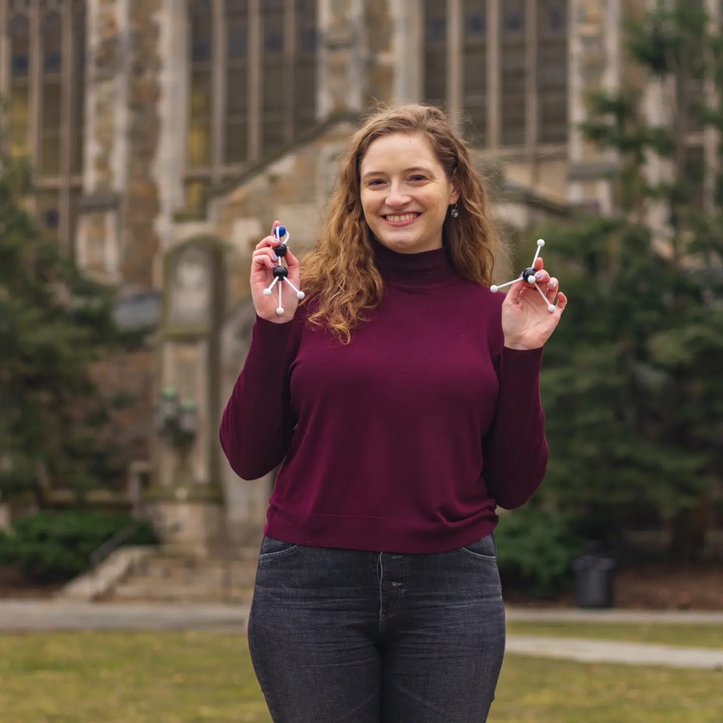 Image of Jenny holding two toy molecules: CH3CN and CH4